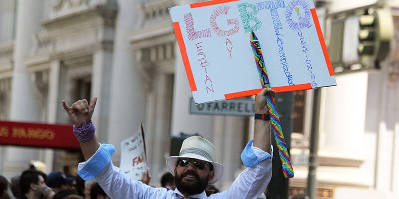 A supporter of LGBTQ rights holding a sign at a rally.