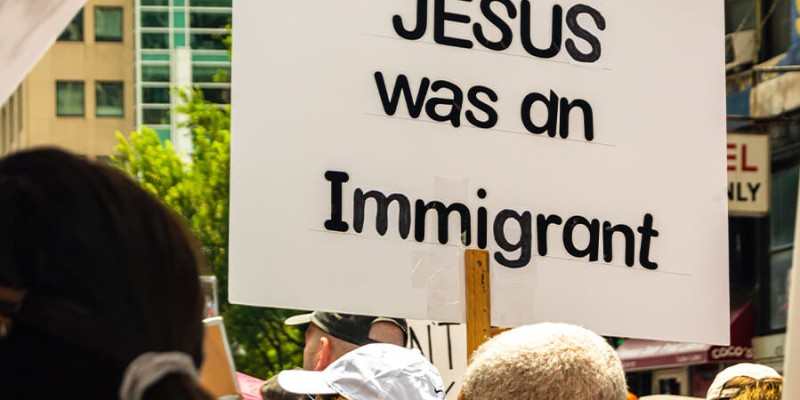 Protesters marching against ICE with a sign that reads "Jesus was an immigrant."