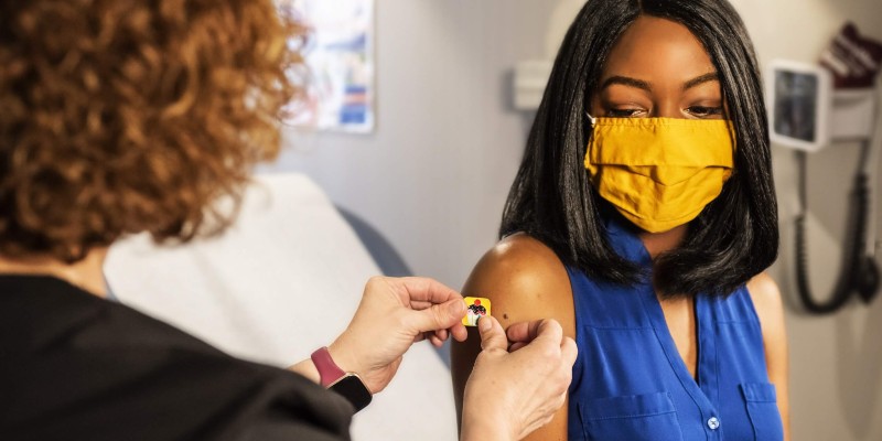 A woman wearing a mask gets a vaccination.