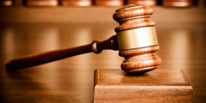 Gavel and sounding block on desk with books seen in the background.