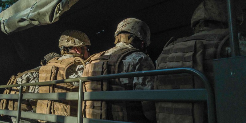 A group of soldiers dressed in full gear sitting in a vehicle.