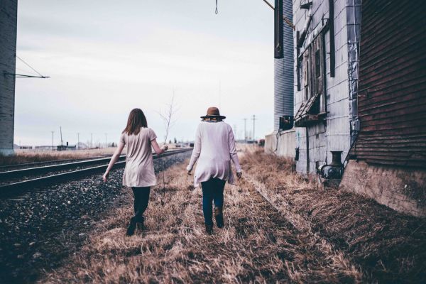Couple walking parallel to a set of train tracks