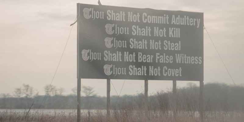 A sign on the side of the highway with some of the ten commandments on it.