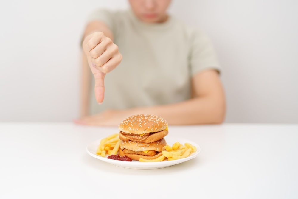 A woman giving a thumbs down to a chicken sandwich