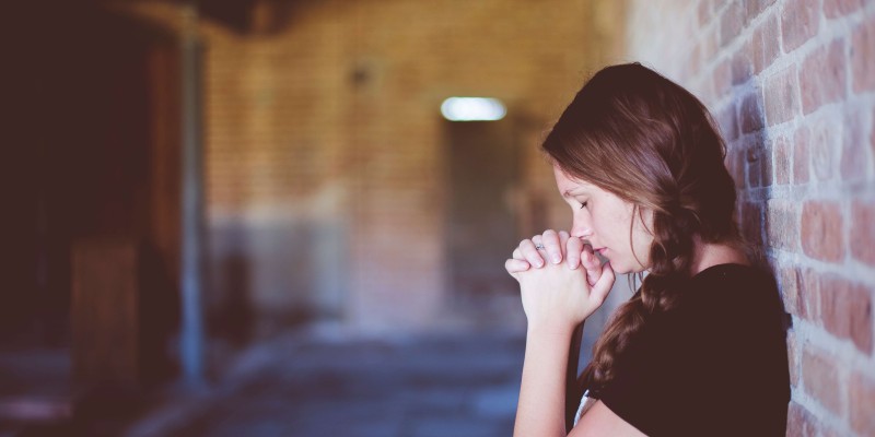 High School Student Praying in a Corridor.