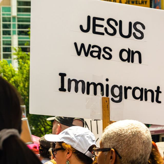 Protesters marching against ICE with a sign that reads "Jesus was an immigrant."