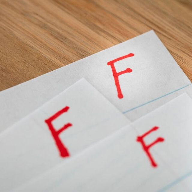 Pieces of paper with a failing grade of 'F' at the top.