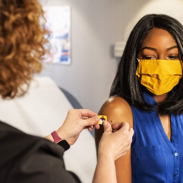 A woman wearing a mask gets a vaccination.