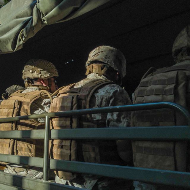 A group of soldiers dressed in full gear sitting in a vehicle.