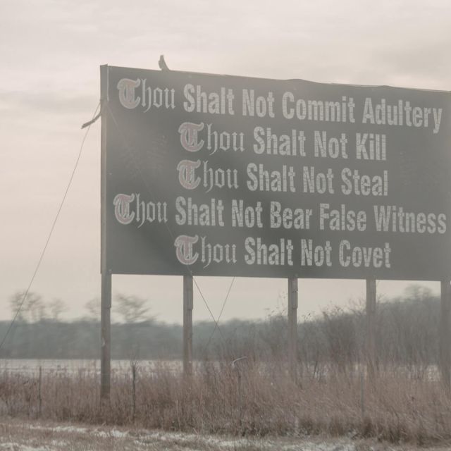 A sign on the side of the highway with some of the ten commandments on it.
