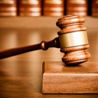 Gavel and sounding block on desk with books seen in the background.