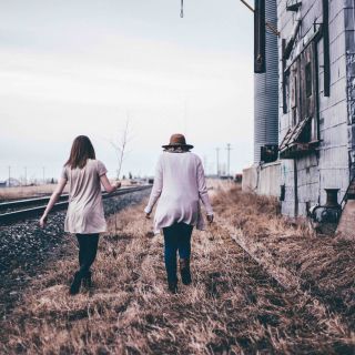 Couple walking parallel to a set of train tracks