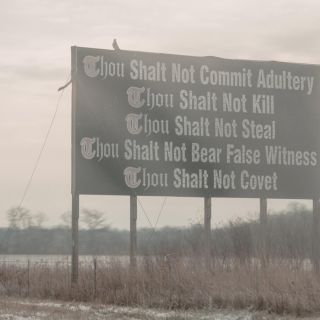 A sign on the side of the highway with some of the ten commandments on it.