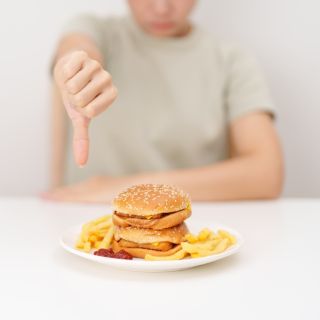 A woman giving a thumbs down to a chicken sandwich
